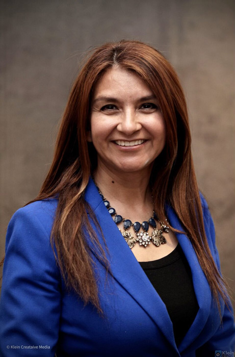 a woman wearing a blue blazer and necklace smiling